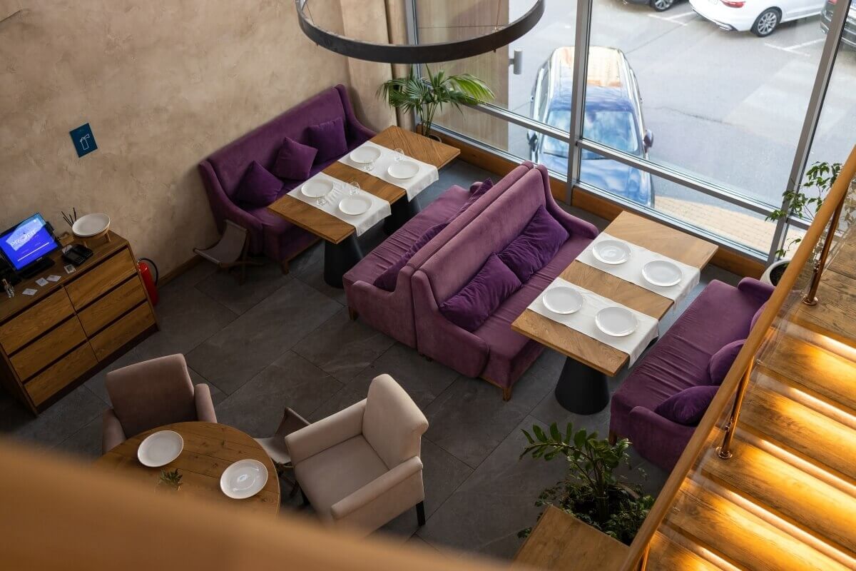 W kawiarni ustawione są eleganckie fotele do kawiarni w kolorach fioletu i beżu.