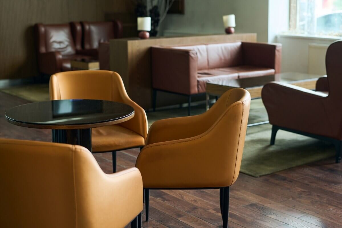 W kawiarni znajdują się eleganckie, skórzane fotele do kawiarni w odcieniach brązu i pomarańczy.