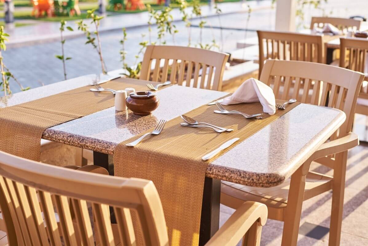 Stoły do kawiarni ustawione na tarasie z nakryciem.