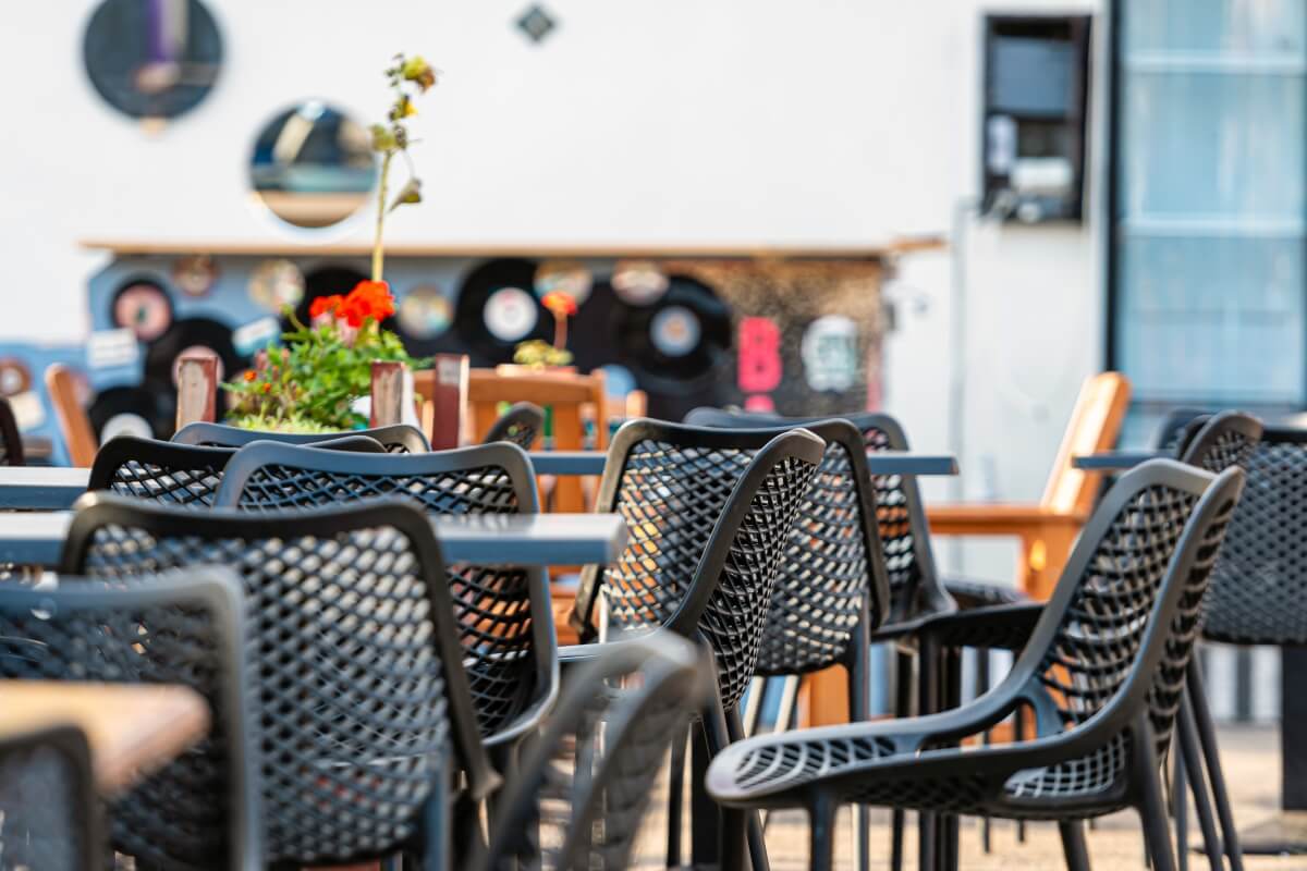 W ogrodowej kawiarni stoją czarne krzesła ogrodowe plastikowe.