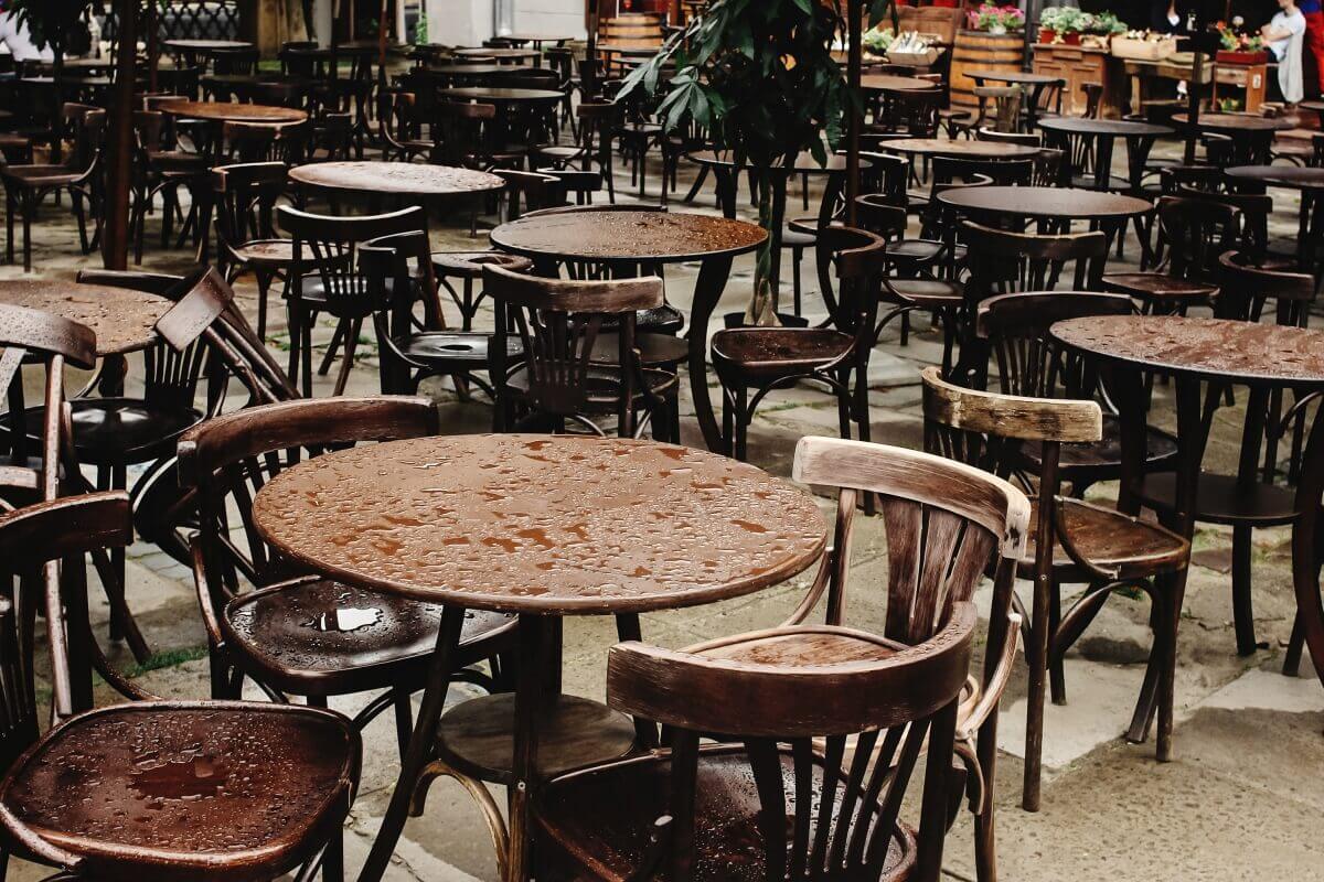 Mokra powierzchnia pełna jest krzeseł i stołów ogrodowych.